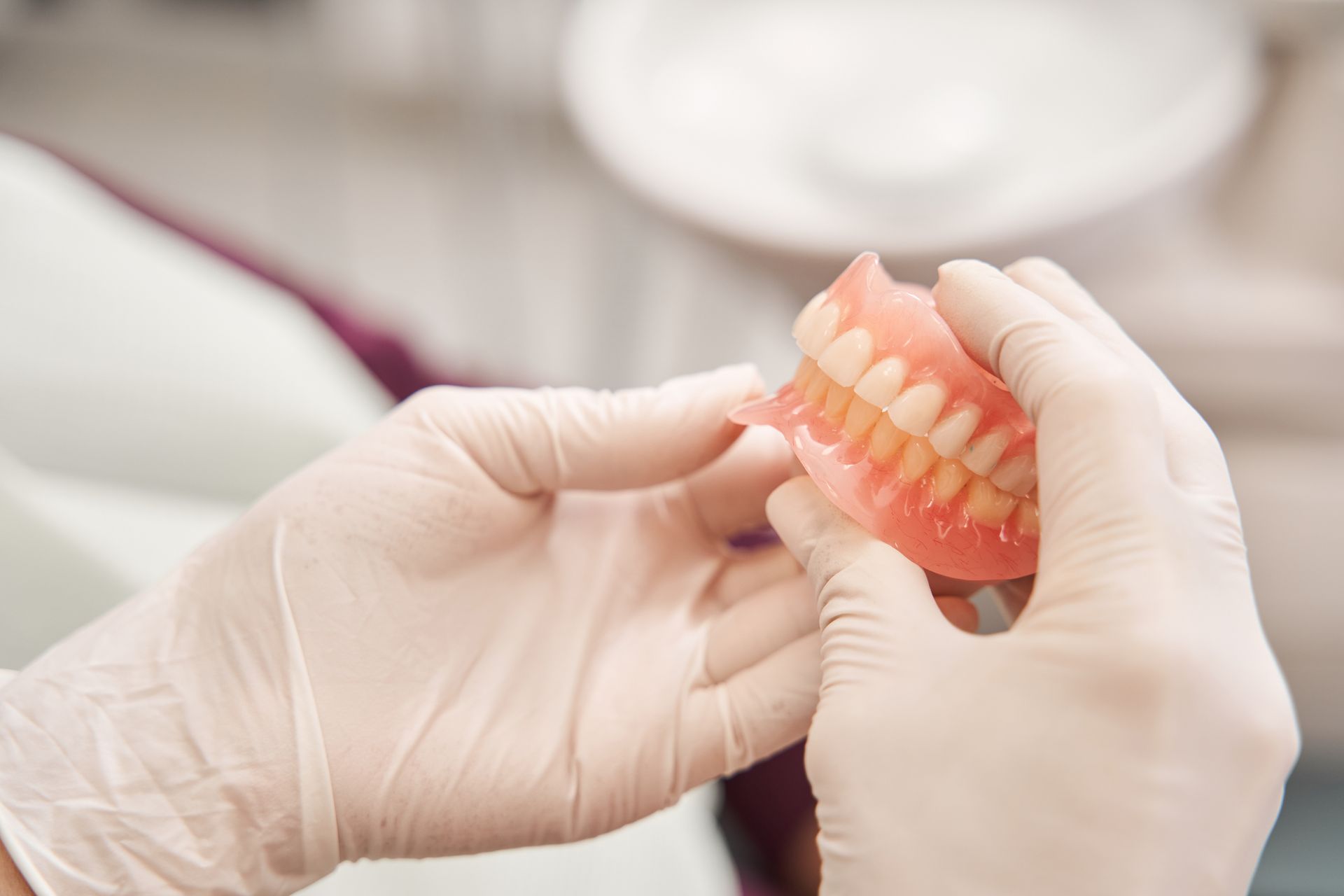 A dental prosthetist holding new dentures in their hands A dental prosthetist holding new dentures in their hands