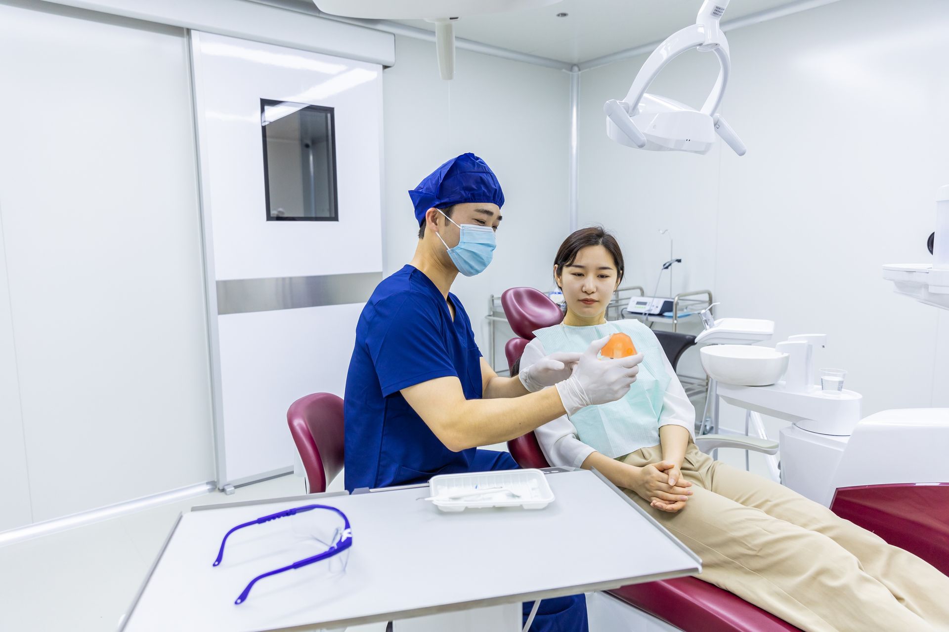 A dentist is showing a dental model to a patient. A dentist is showing a dental model to a patient.