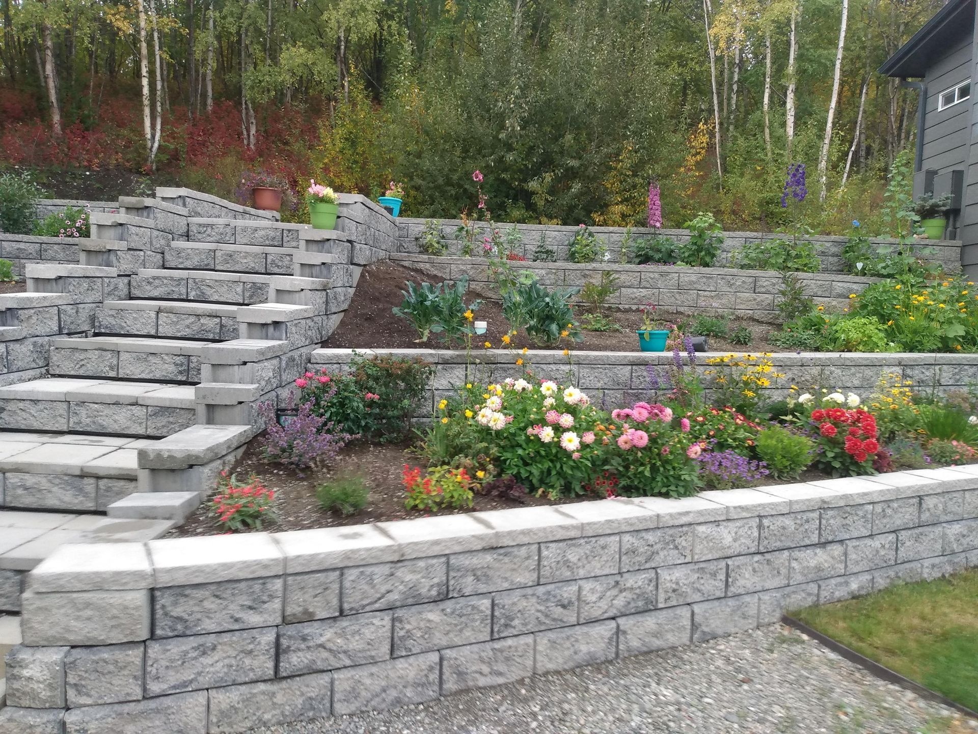 A brick wall surrounded by flowers and stairs in a garden.