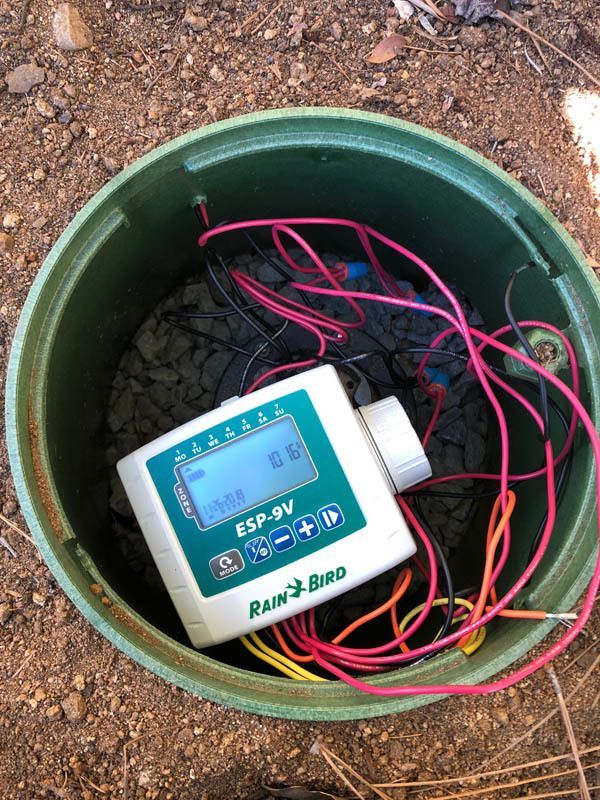 A sprinkler controller is sitting inside of a green container