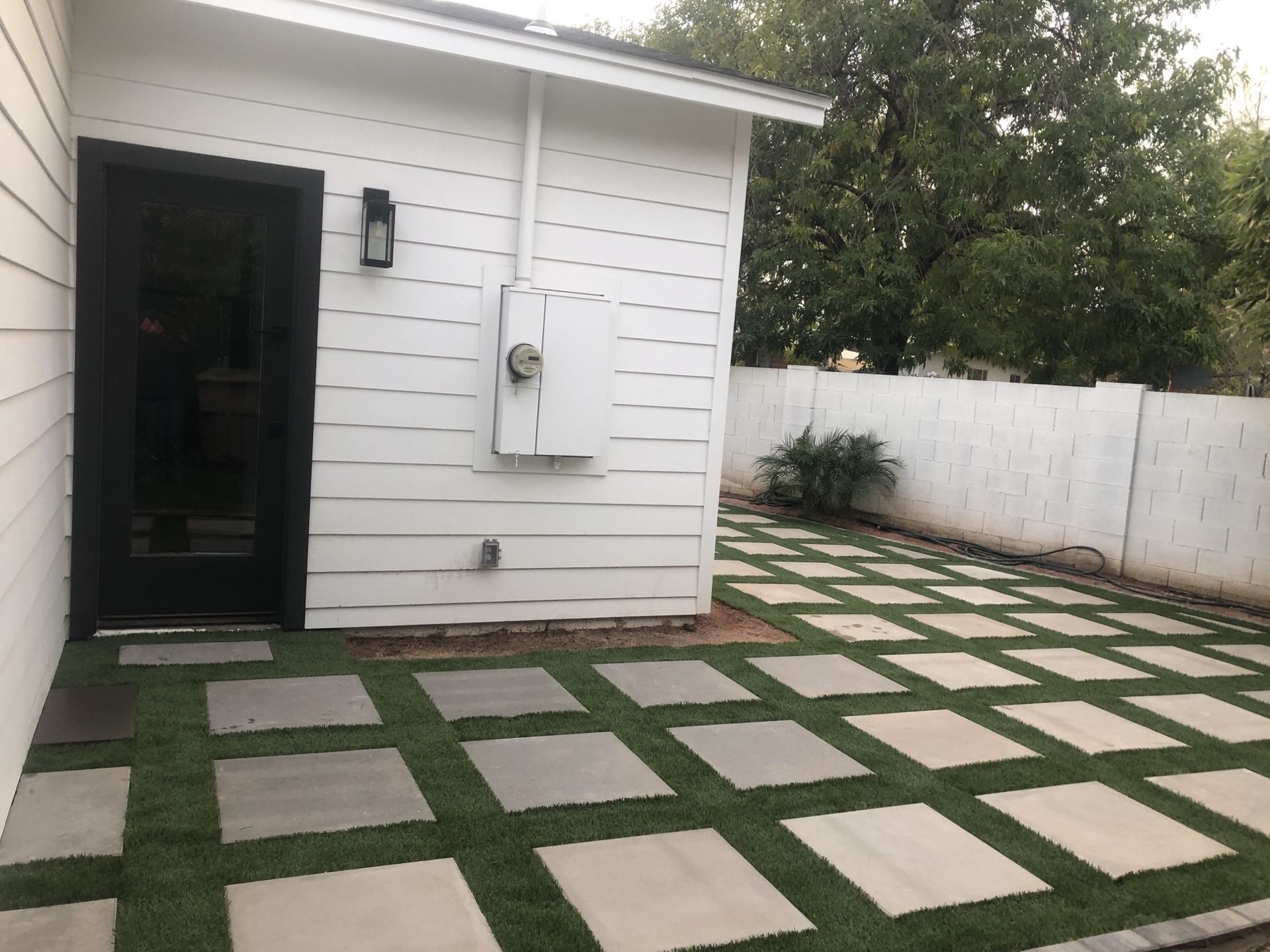 A white house with a black door and a lawn in front of it
