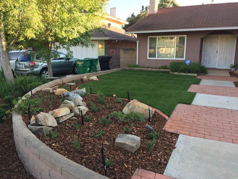 A house with a lush green lawn and a brick walkway in front of it