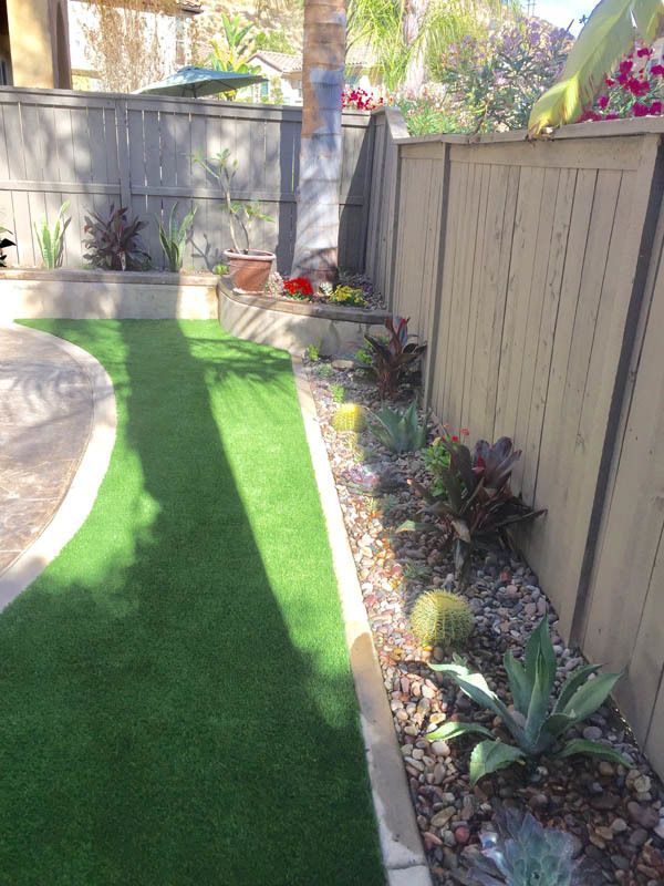 A backyard with a wooden fence and a lush green lawn