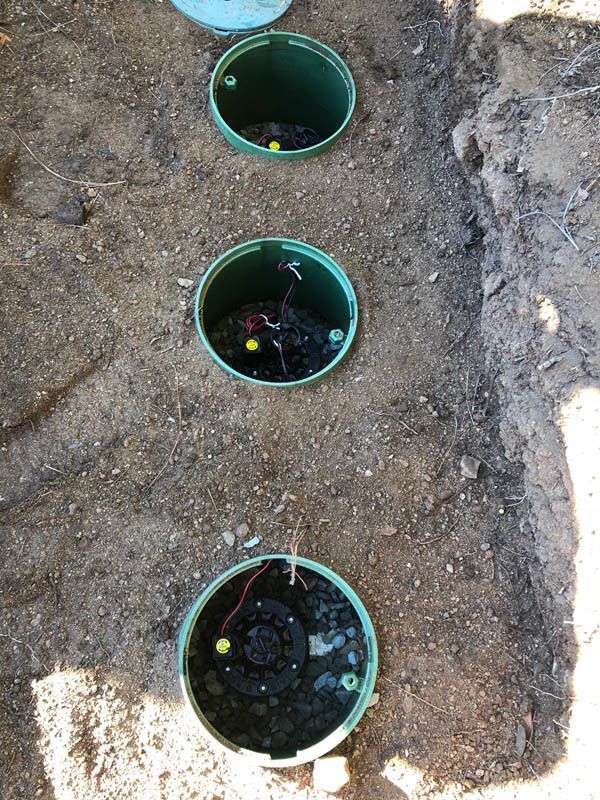 Three green buckets are sitting on top of a pile of dirt