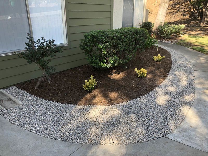 A circular walkway with gravel and plants in front of a house