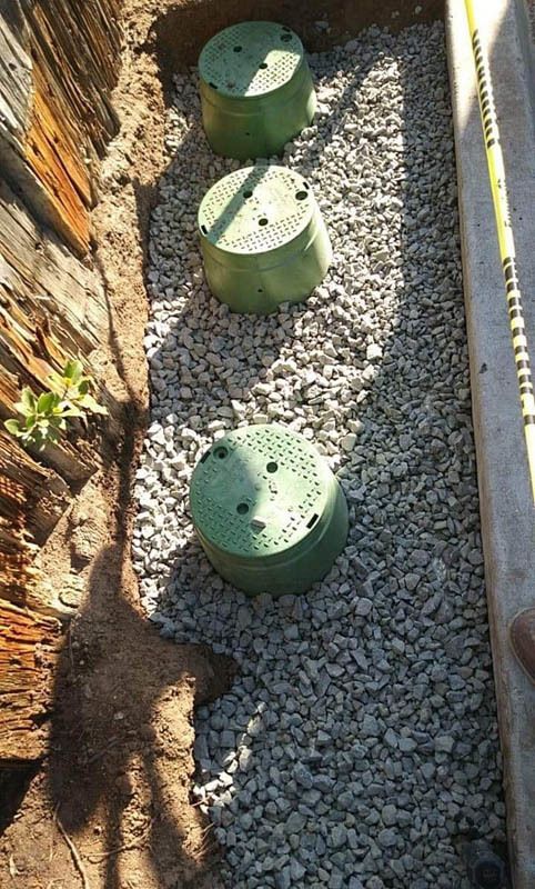 Three green boxes are sitting on top of a pile of gravel