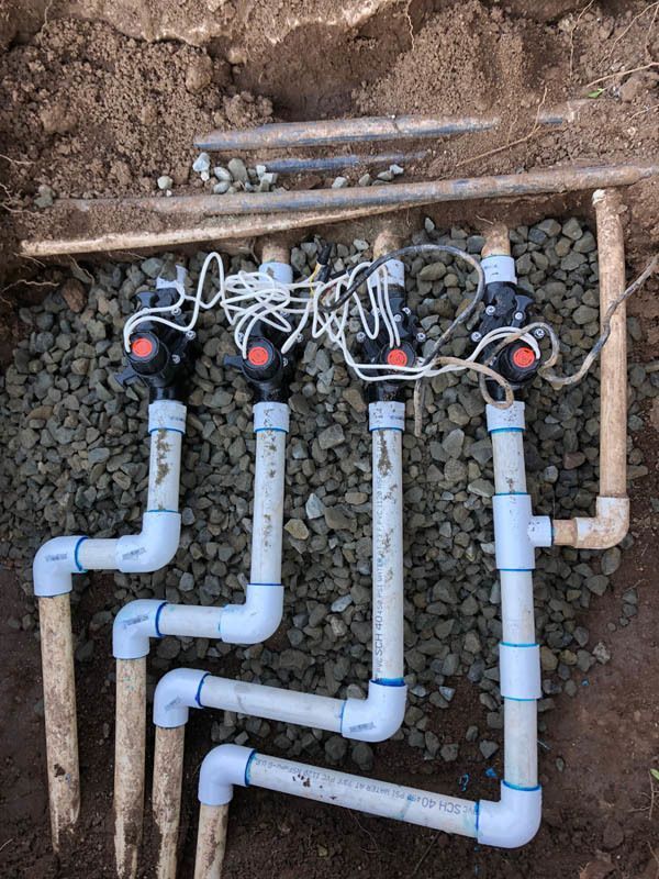 A bunch of pipes are laying in the dirt