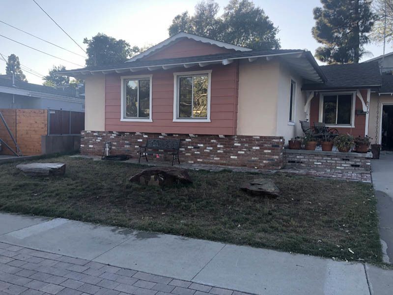A small house with a lot of windows and a brick wall