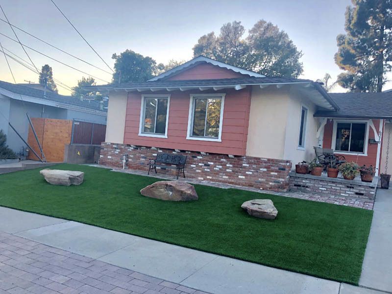A small house with a lush green lawn in front of it