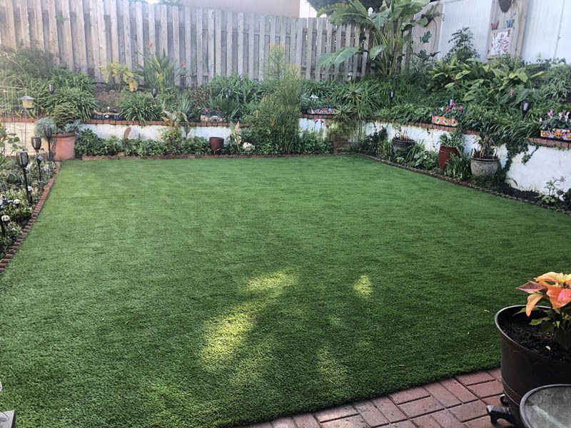 A backyard with a large lawn and a brick patio