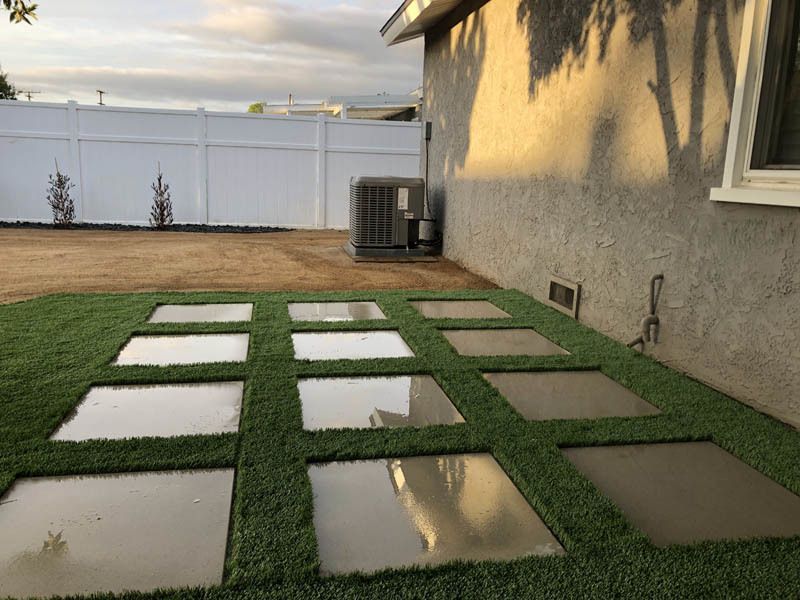 A lawn with a white fence and a white air conditioner in the backyard