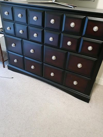 Dark wood dresser with many drawers and silver knobs.