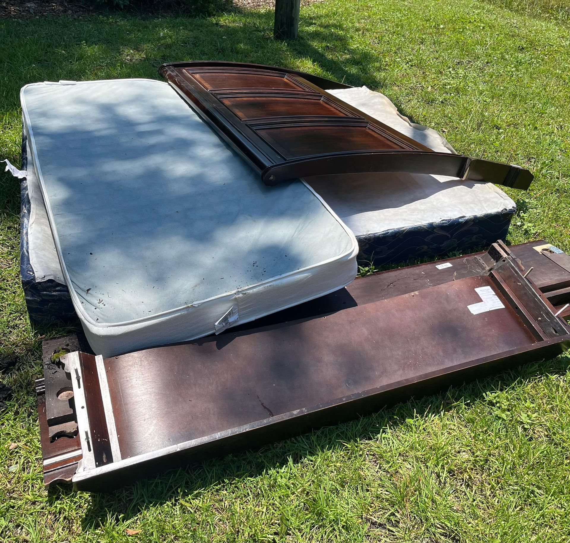Discarded mattress parts and furniture on grass.