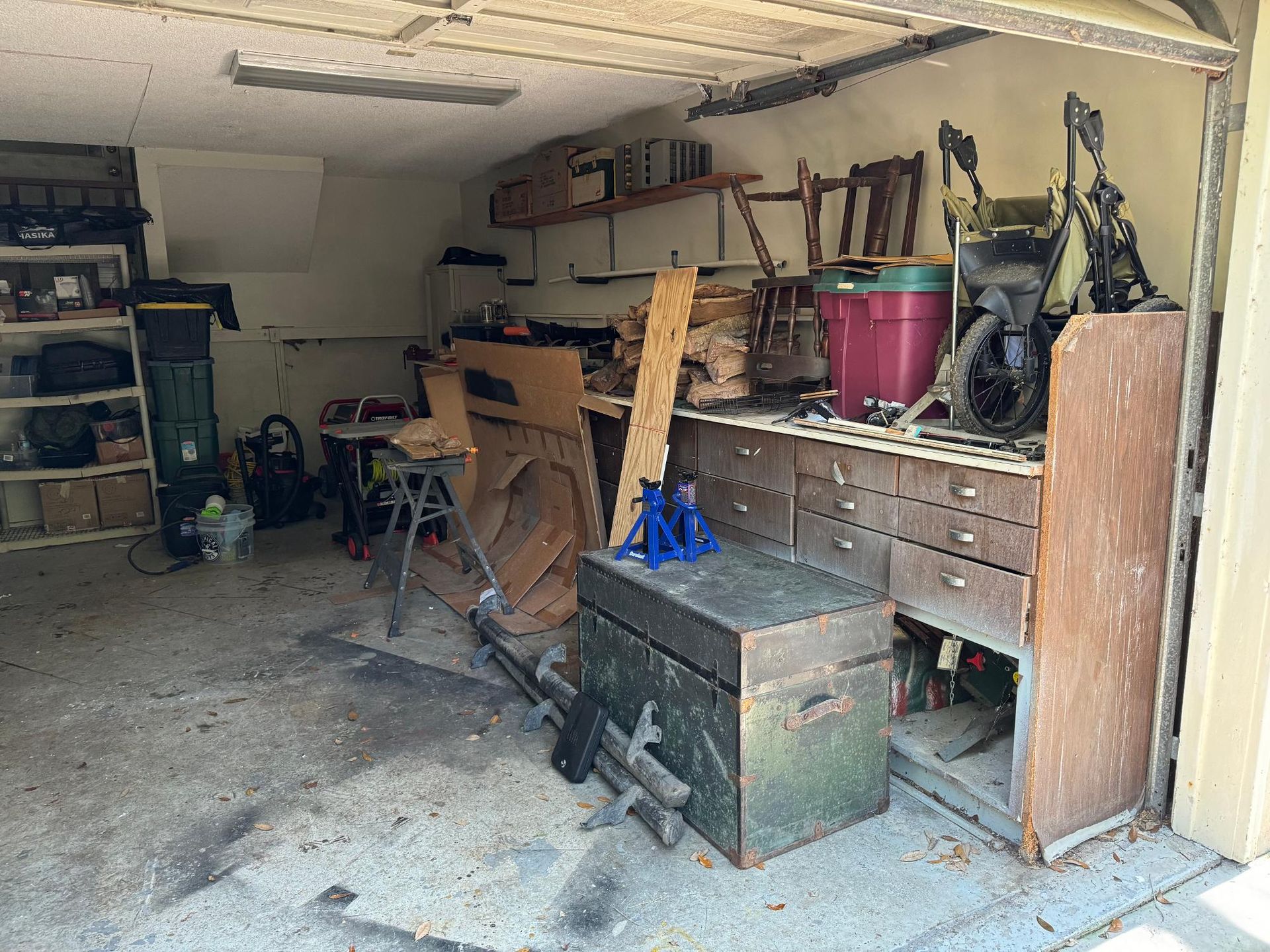 Messy garage interior with workbench, tools, and storage cabinets.