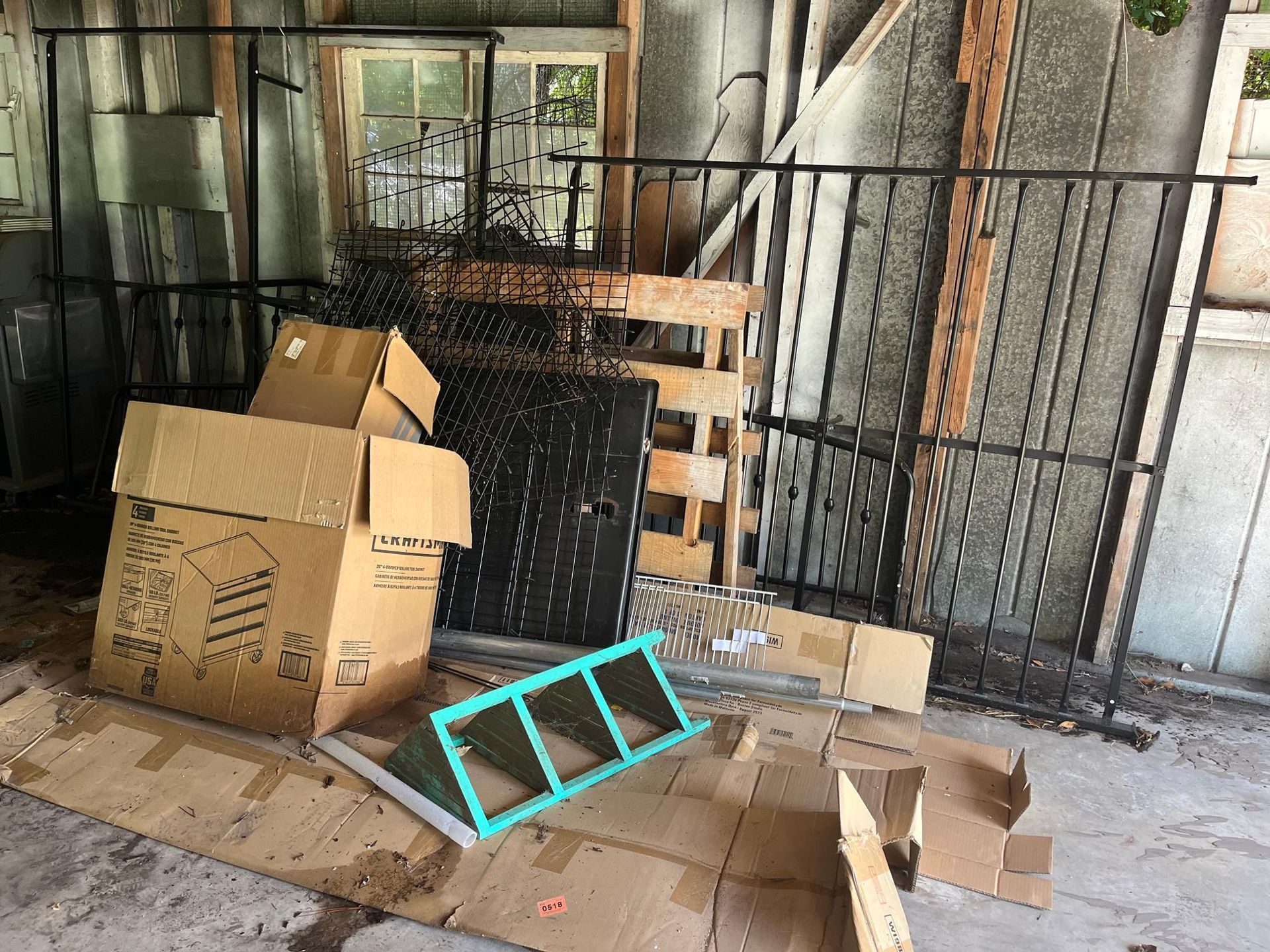 A cluttered garage with boxes, metal railings, and a window frame.