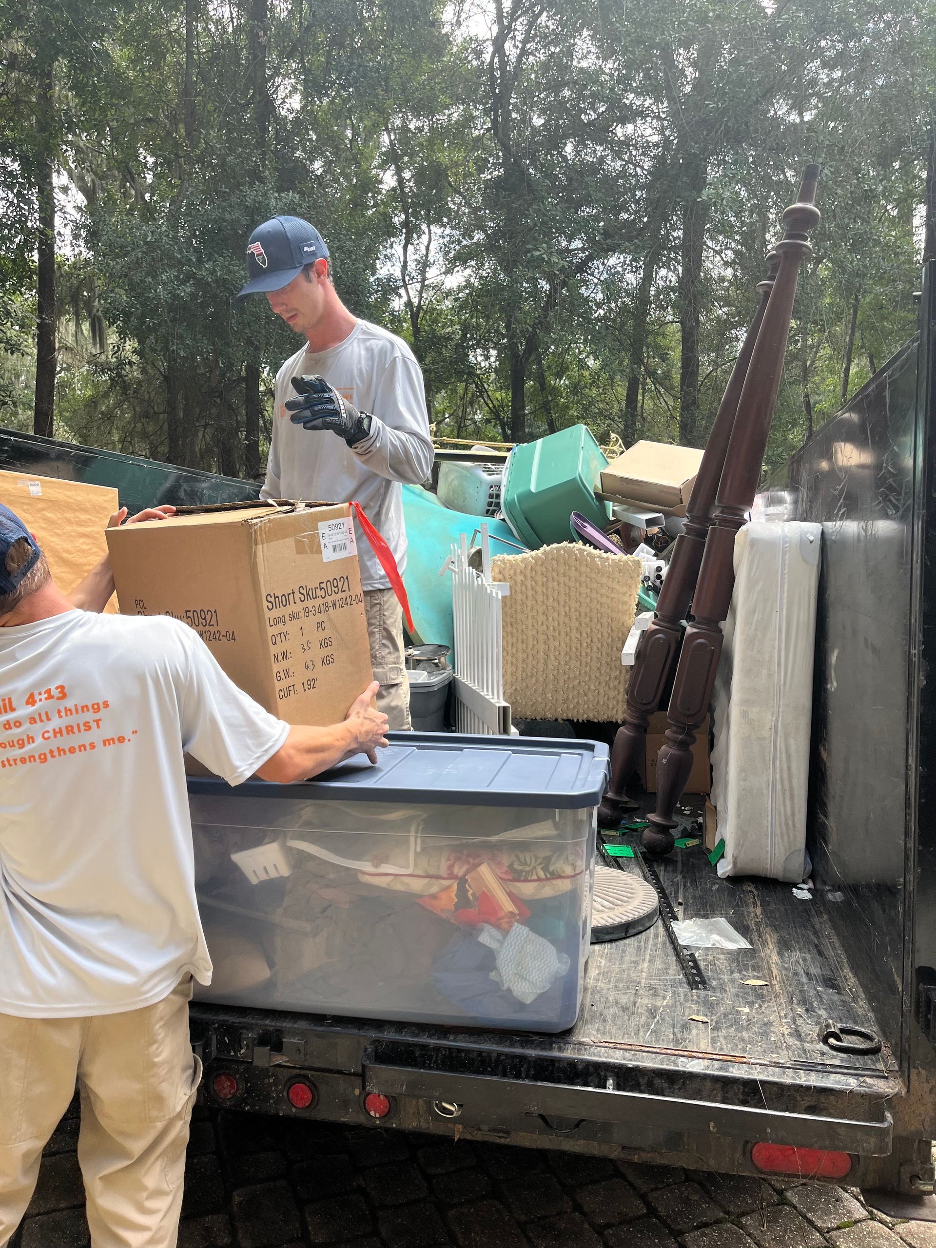 Two men loading furniture and boxes into a truck outdoors.