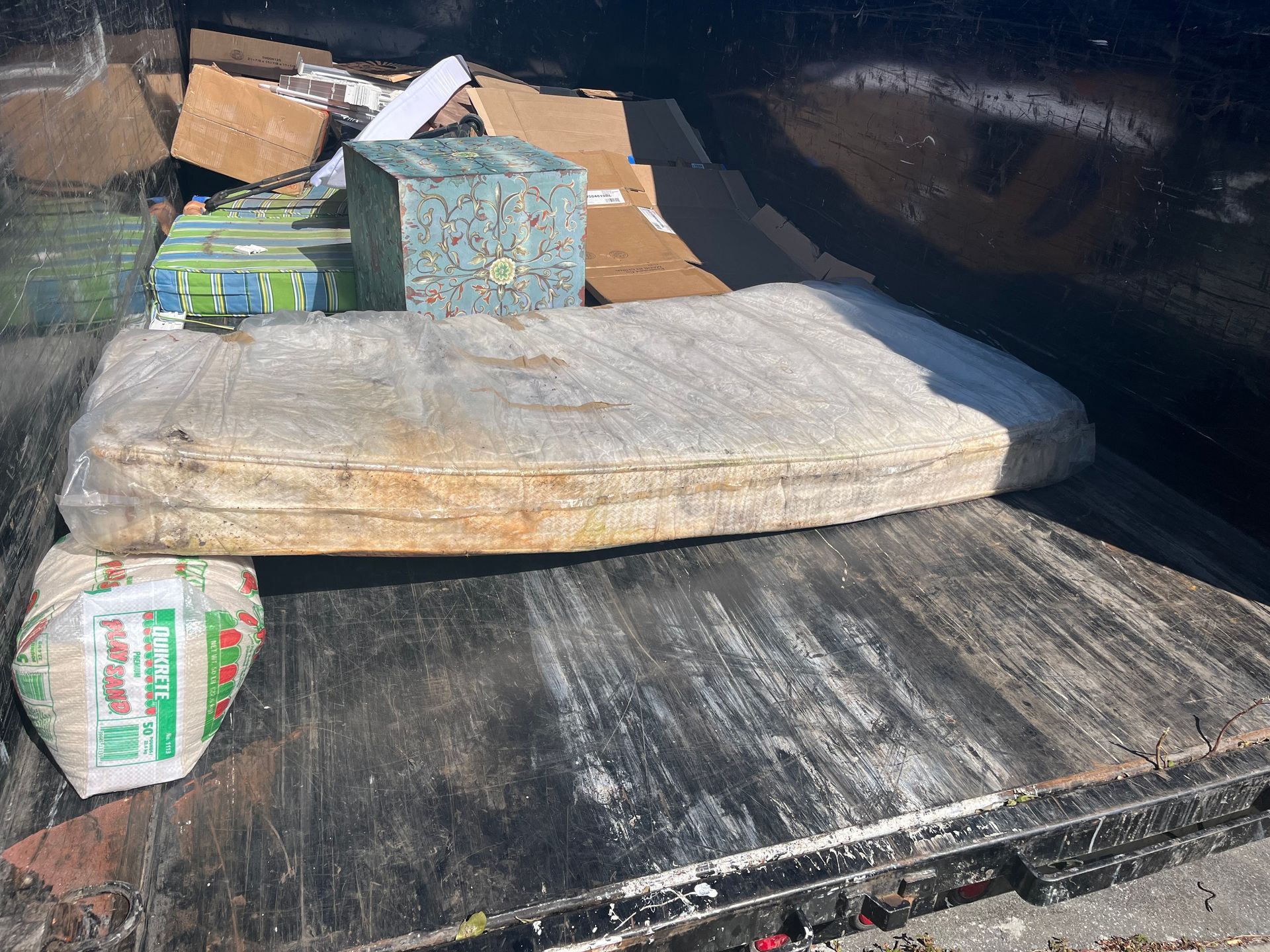 Mattress, boxes, and trash in a dumpster.