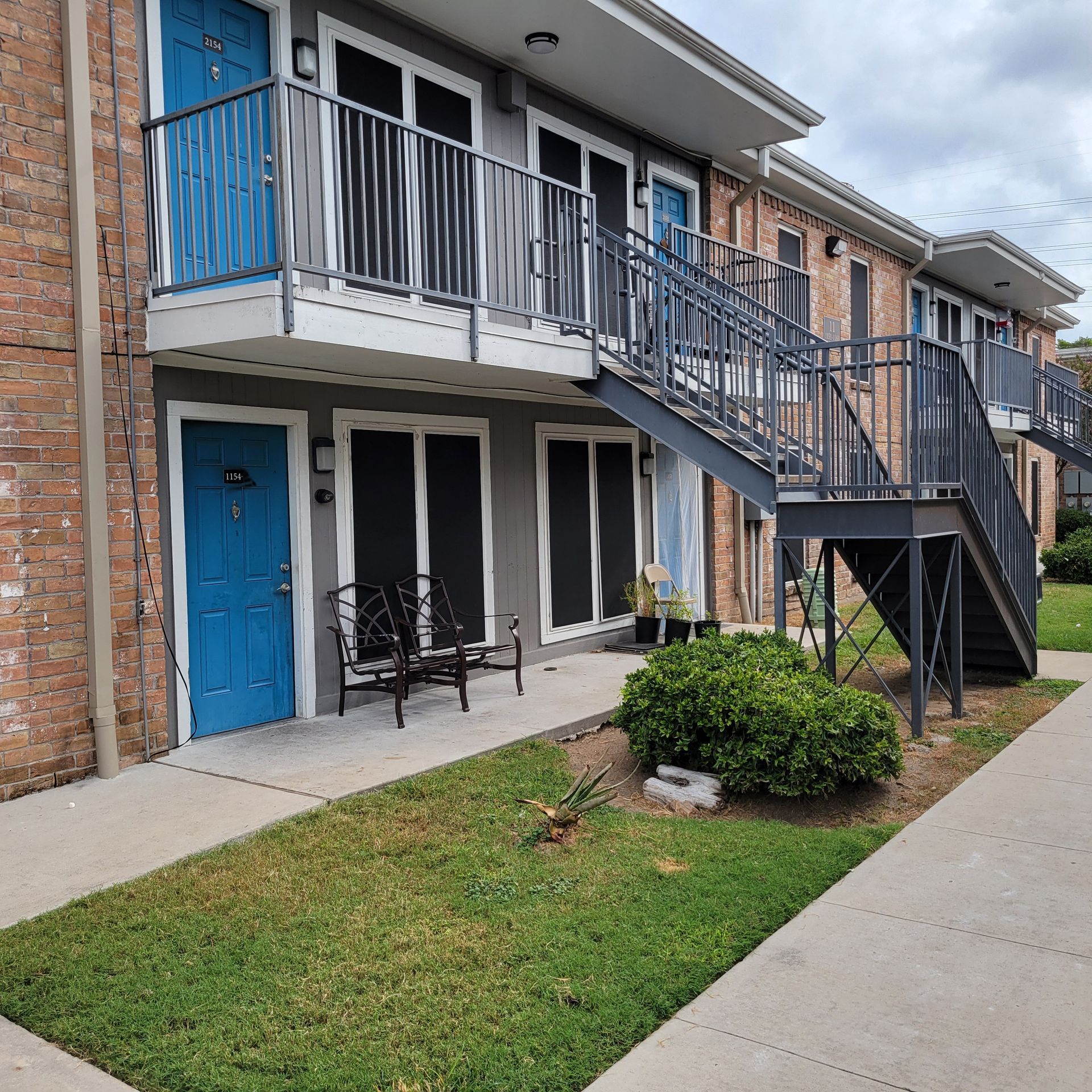 A brick apartment building with blue doors and stairs