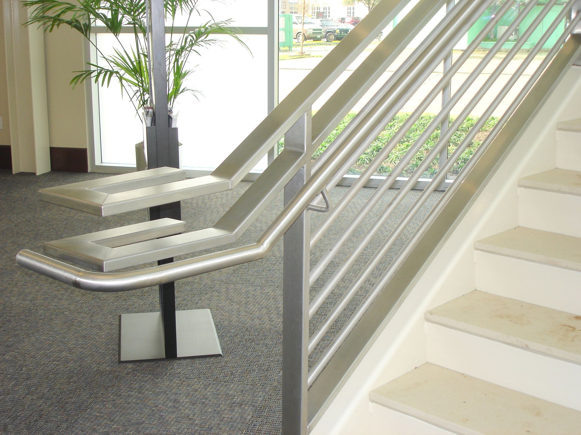 A staircase with a stainless steel railing and concrete steps