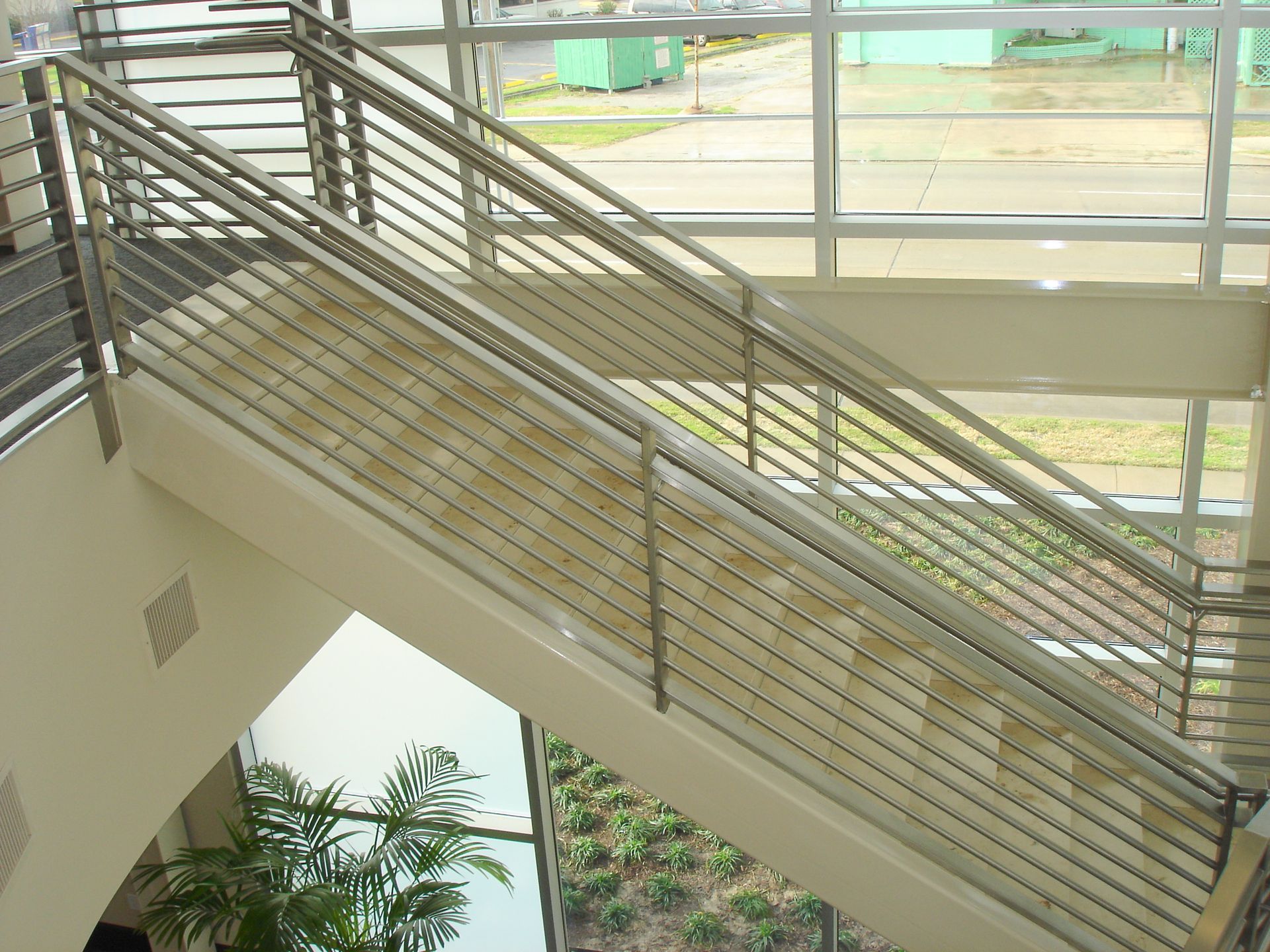 A staircase in a building with a stainless steel railing