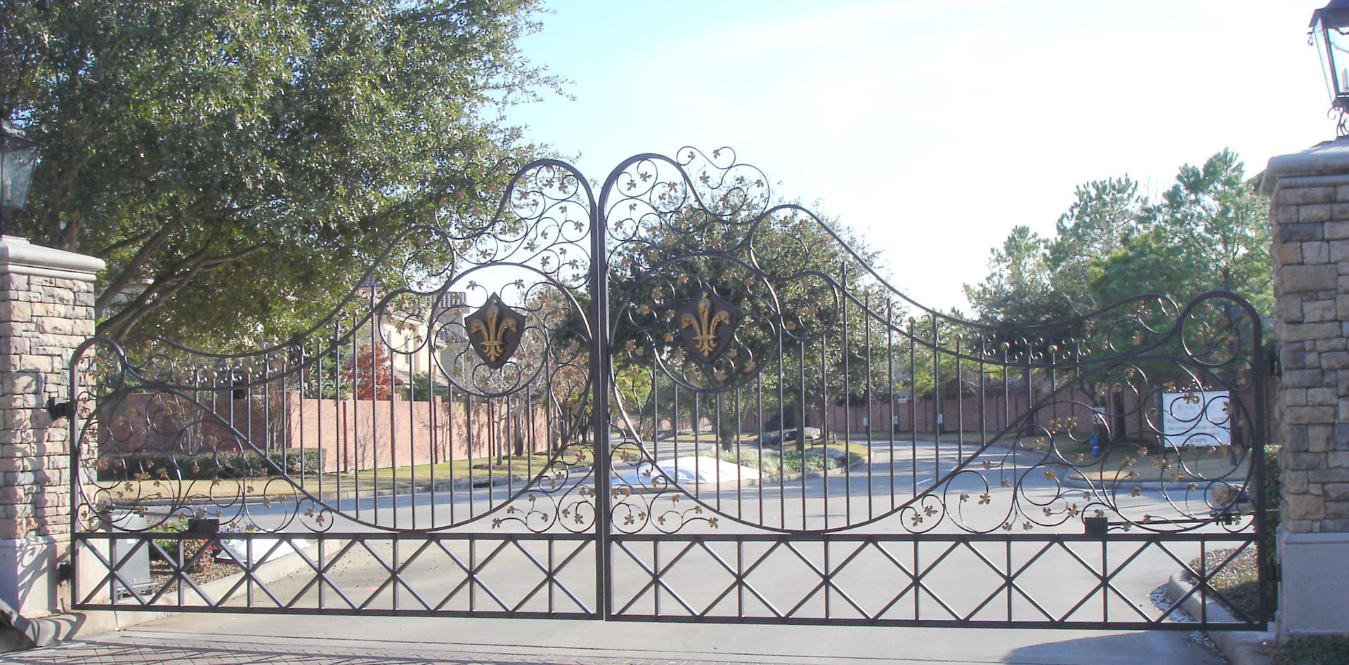 A wrought iron gate is open to a driveway