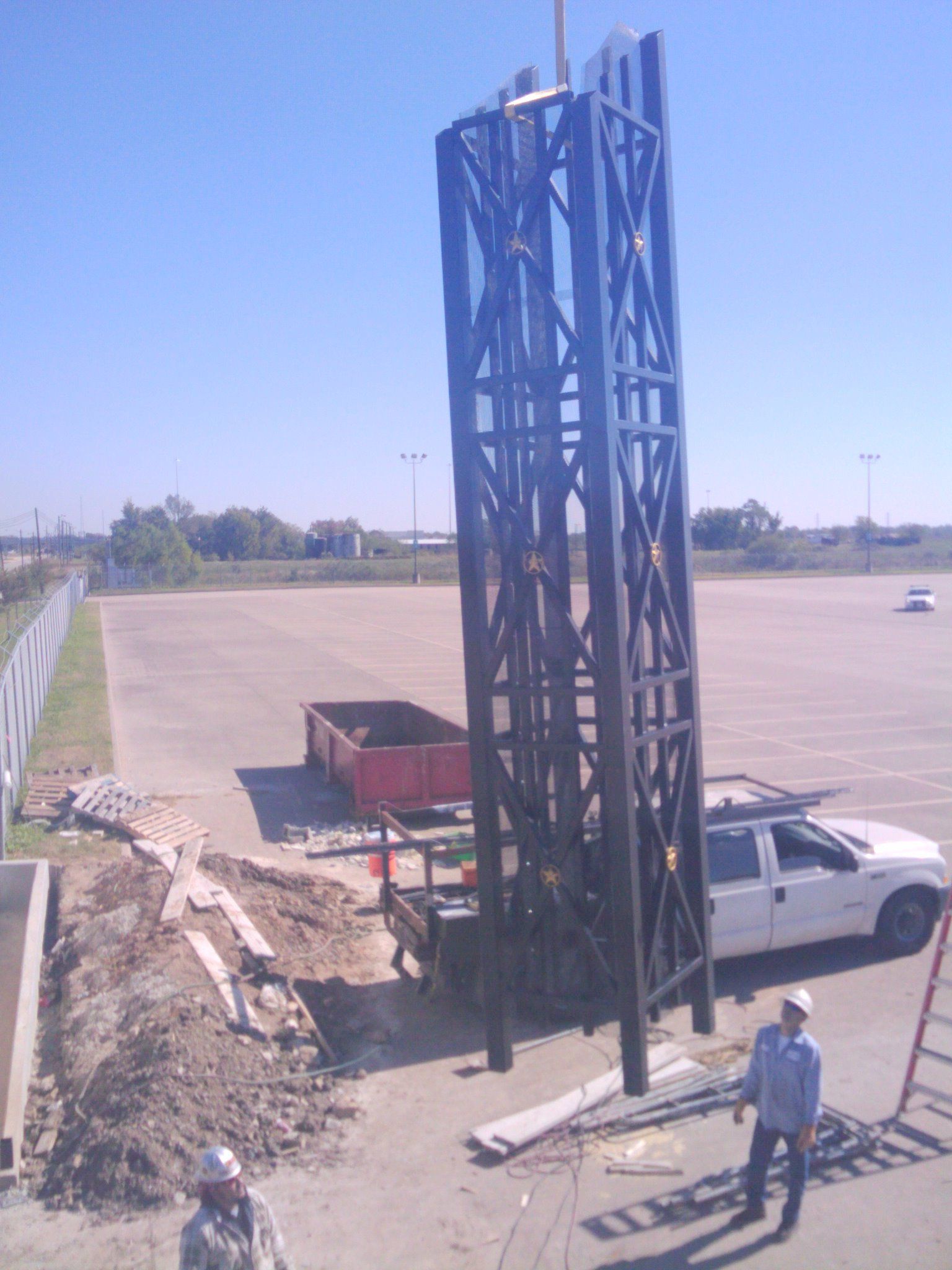 A white truck is parked in a parking lot next to a large metal structure