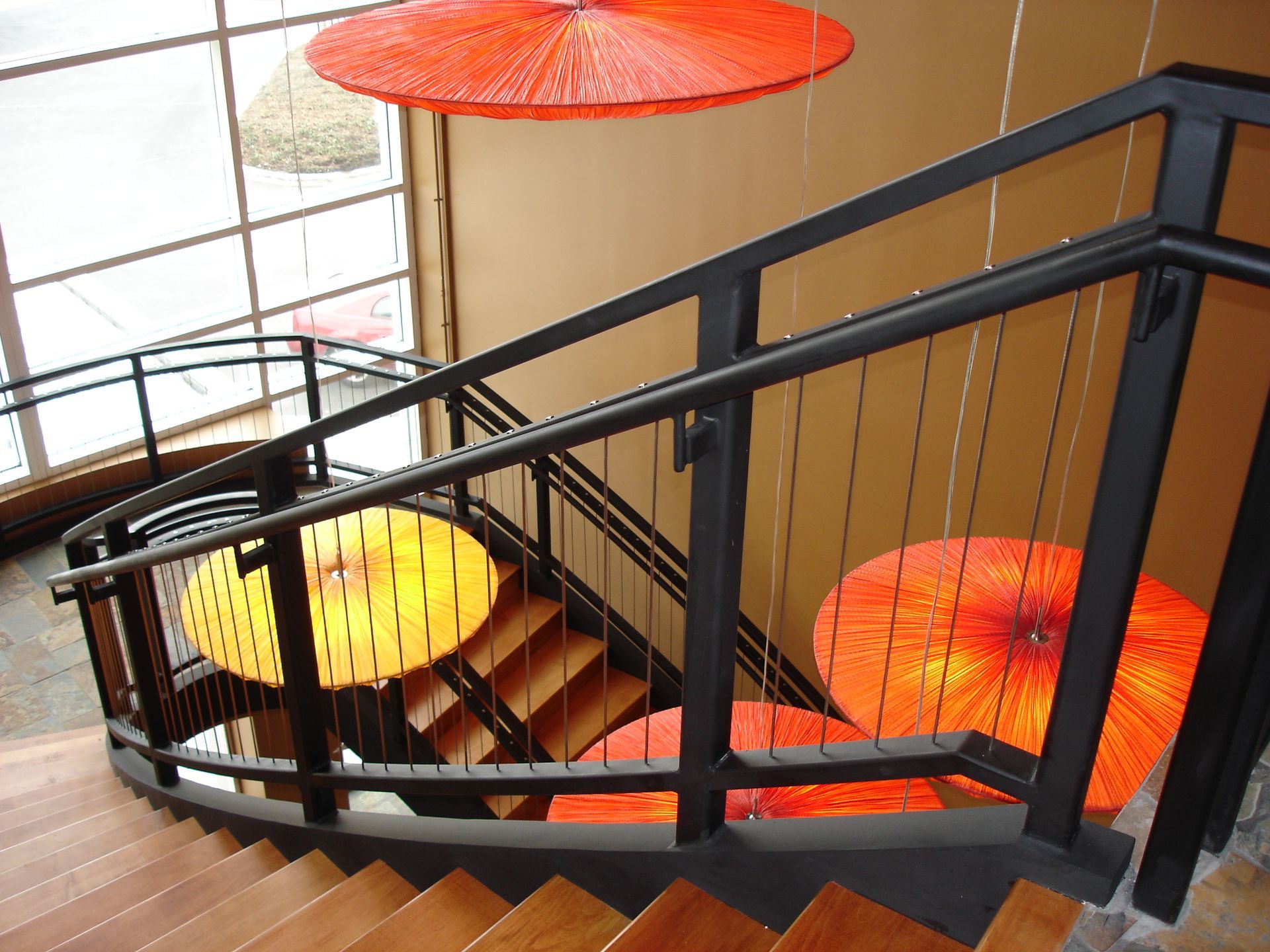 A staircase with red umbrellas hanging from the ceiling