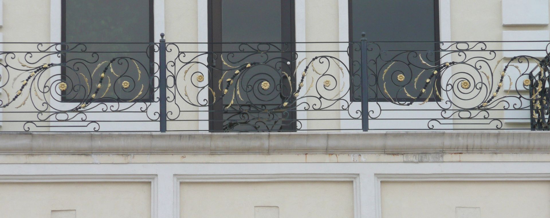 A balcony on the side of a building with a wrought iron railing.