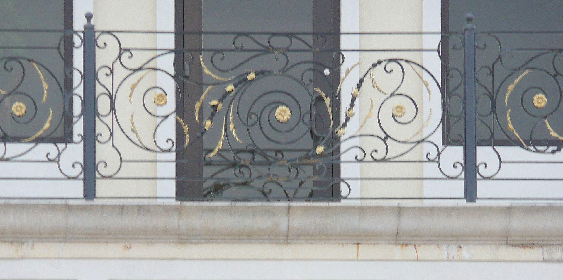 A wrought iron fence surrounds a balcony on a building