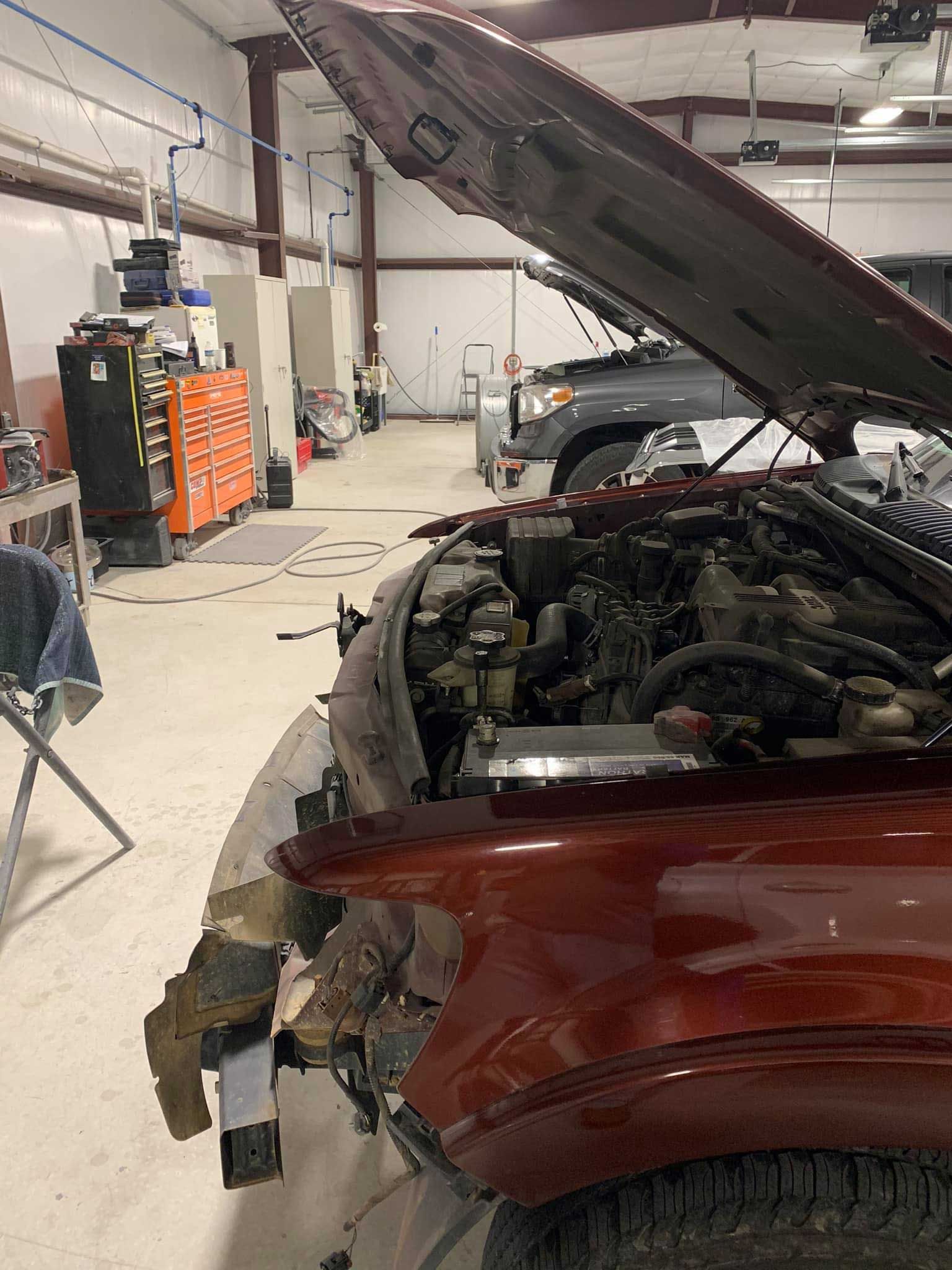 A red truck with its hood up in a garage.