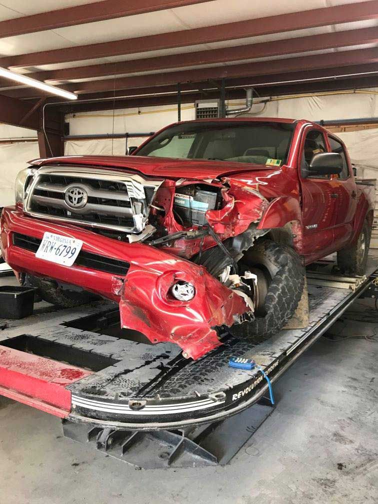 A red truck is sitting on top of a tow truck in a garage.