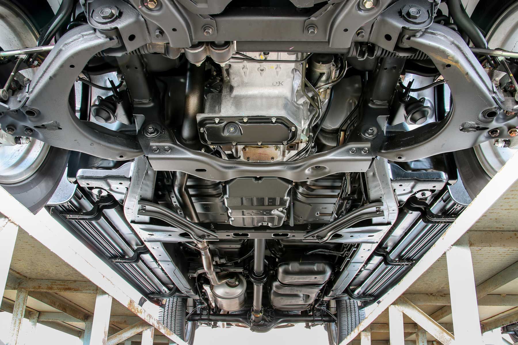The underside of a car is shown in a garage.