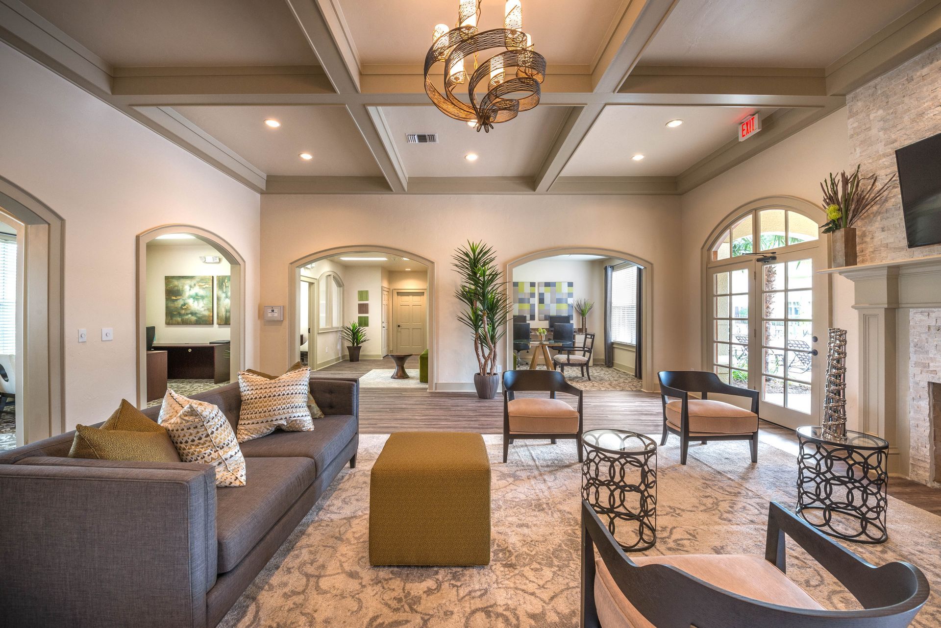 Spacious, well-lit lounge area with couches, chairs, and a patterned rug, leading to arched doorways.