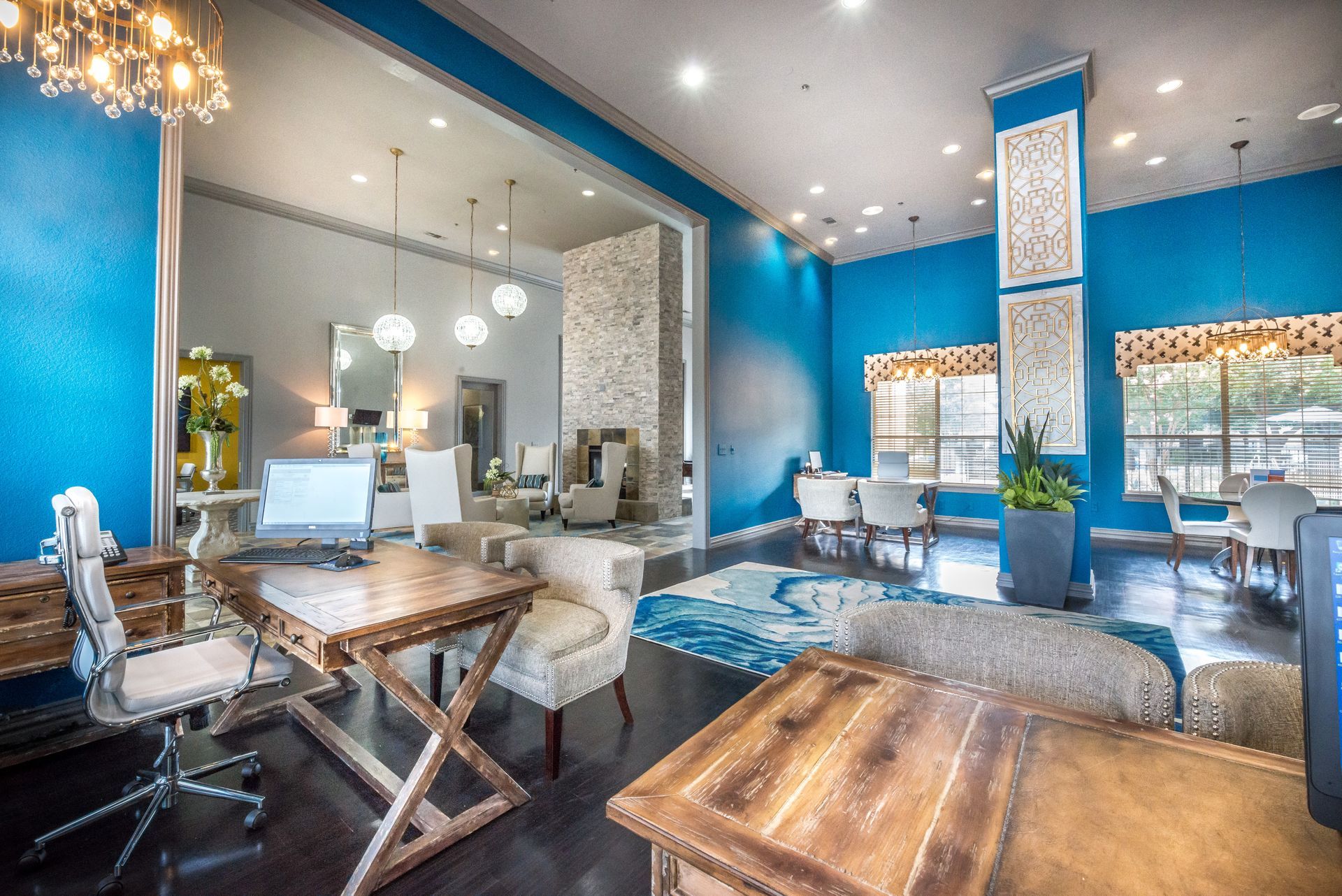 Lobby with blue walls, wood tables, and various seating areas. A doorway leads to another room.
