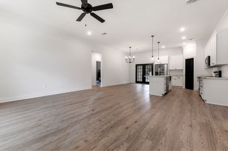 Open-concept living space with hardwood floors, white walls and cabinets, black accents, and a kitchen island.