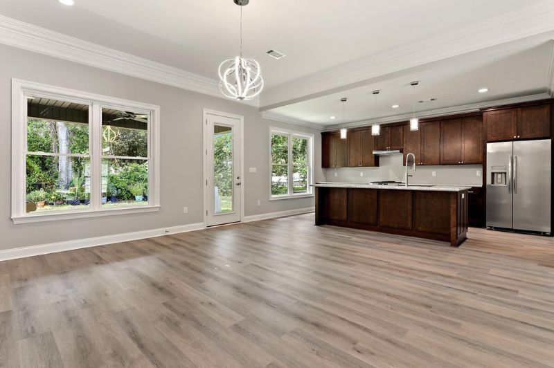 Spacious, open-concept kitchen and living area with wood flooring, cabinetry, and windows.