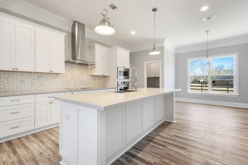 Bright white kitchen with an island, stainless steel appliances, and light gray walls.