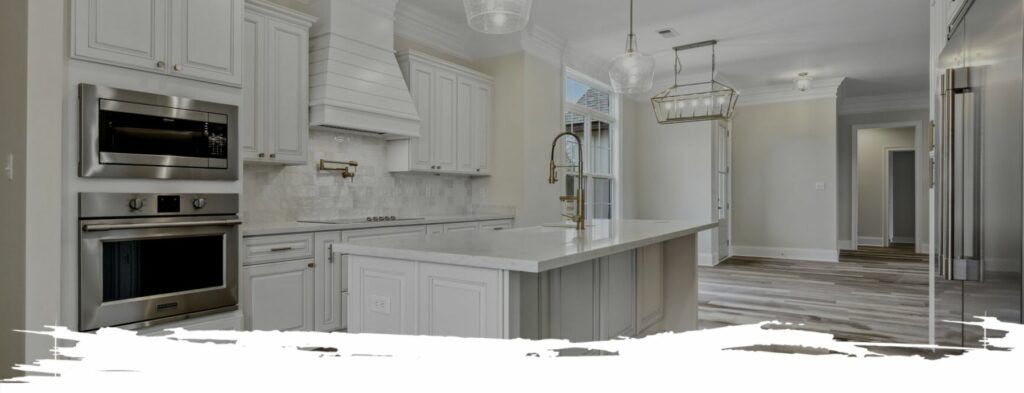 Modern white kitchen with island, appliances, and hardwood floors.