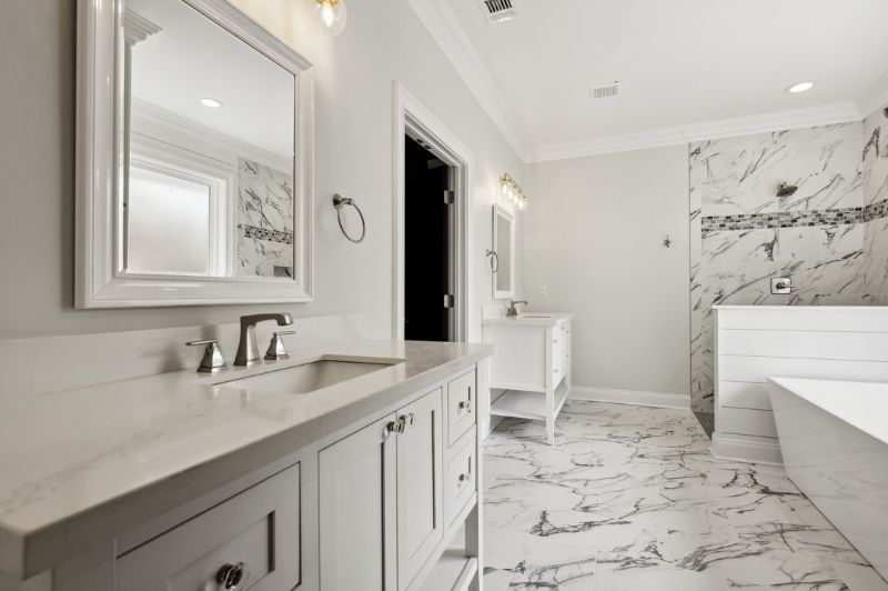 A white bathroom with marble floors, a vanity, and a shower featuring a marble wall.