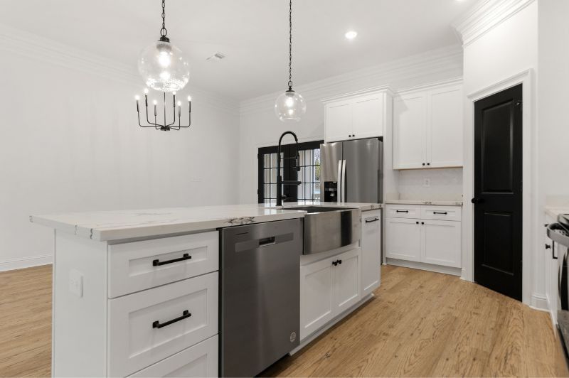 Modern white kitchen with island, stainless steel appliances, and light wood floors.
