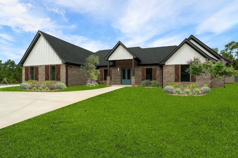 Brick house with black roof, brown shutters, and green lawn under a blue sky.