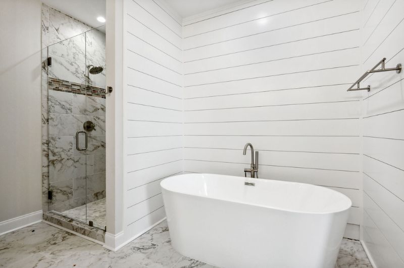 Bright white bathroom with a standalone tub, glass shower, and shiplap walls.