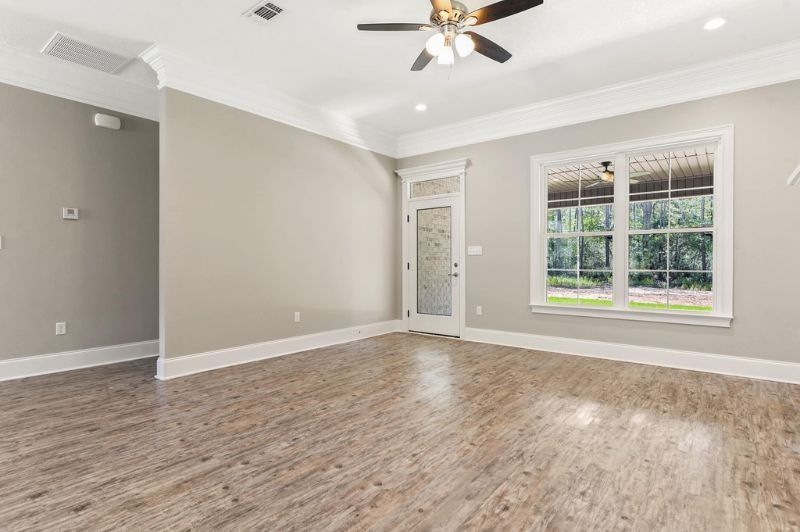 Empty room with wooden floor, light gray walls, white trim, and a glass door and window.