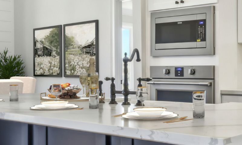 Kitchen island with place settings, faucet, microwave, and oven. Artwork and food on a tray.