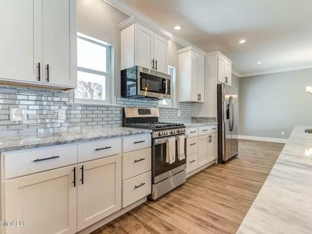 White kitchen with stainless steel appliances, white cabinets, and light gray countertops.