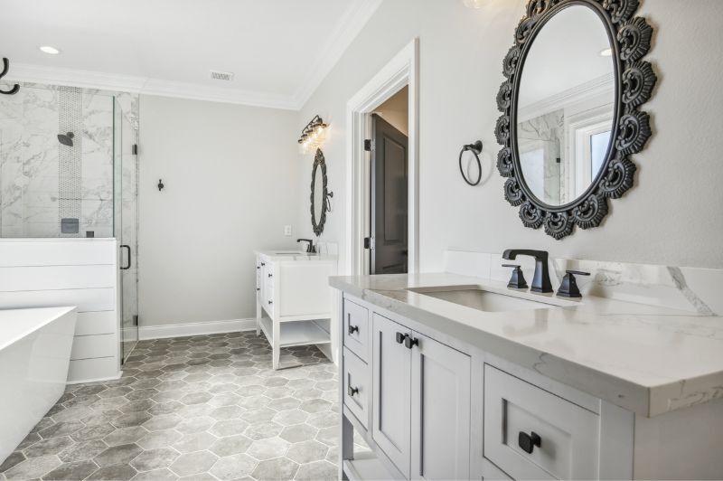 Bathroom with two white vanities, gray tile floor, and decorative black mirrors.