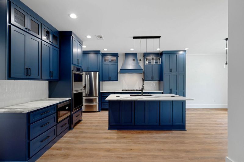 Blue kitchen with island and stainless steel appliances.