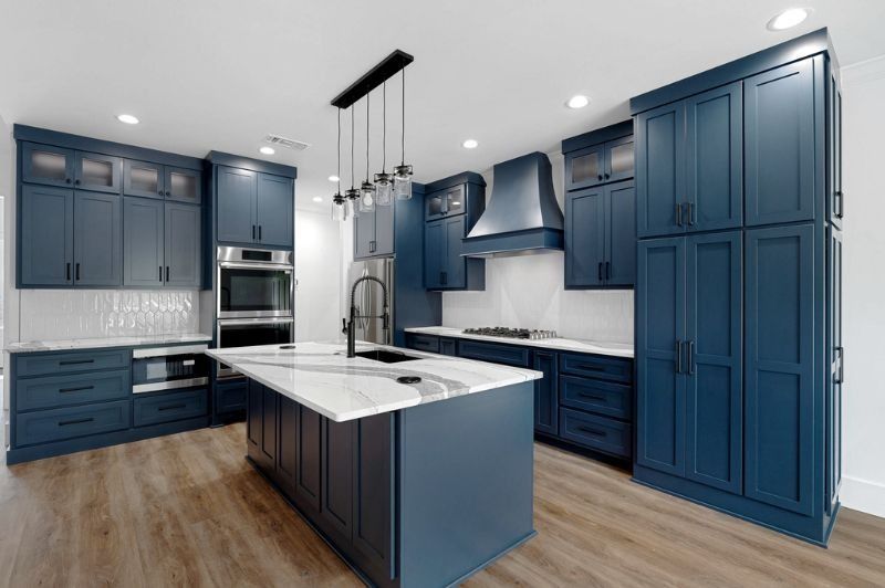 Modern kitchen with navy blue cabinets, white countertops, and a central island.