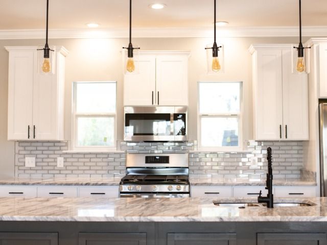 Modern kitchen with white cabinets, granite countertop, and pendant lights.