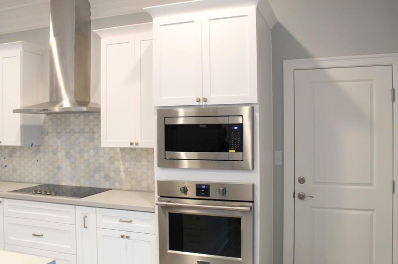 White kitchen with stainless steel microwave and oven built into the cabinetry.